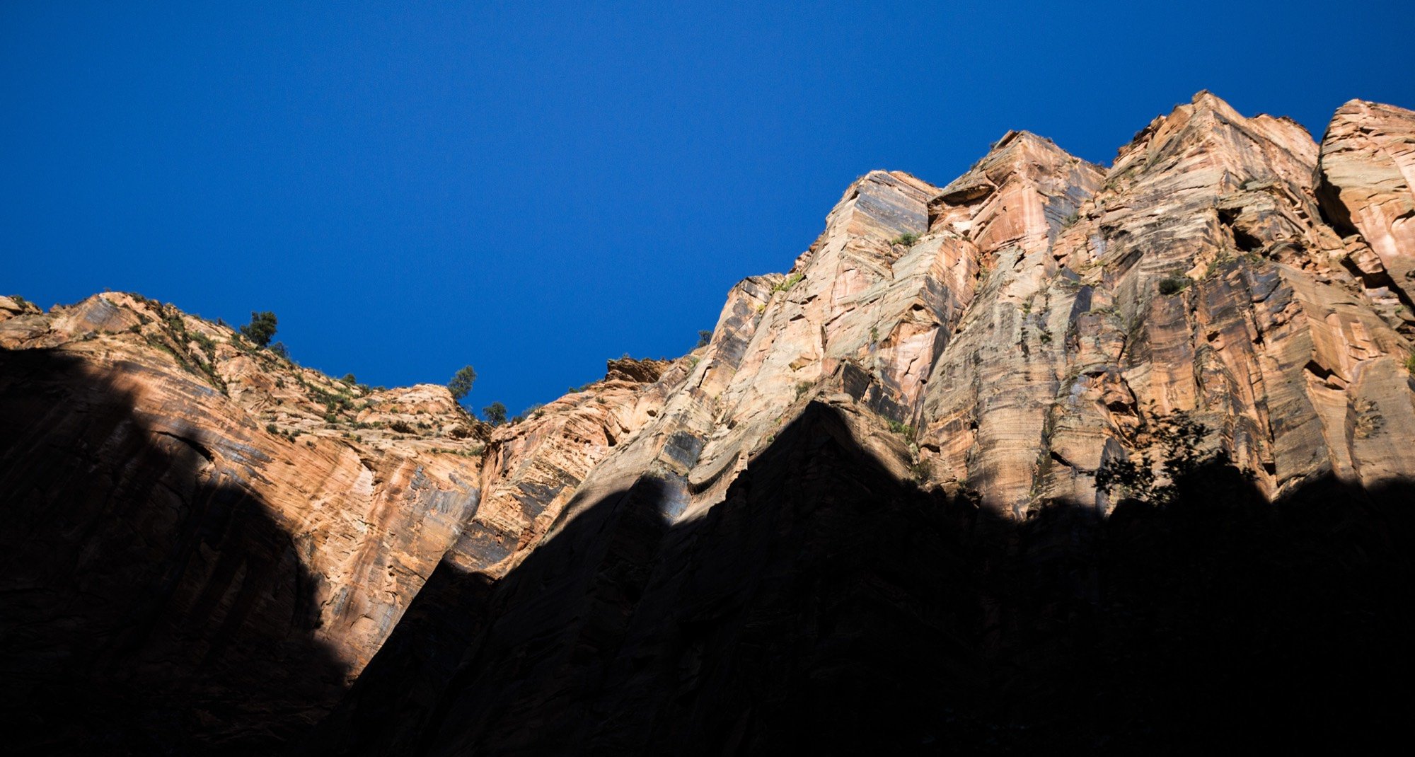 Sunlit red sandstone cliffs against a deep blue sky