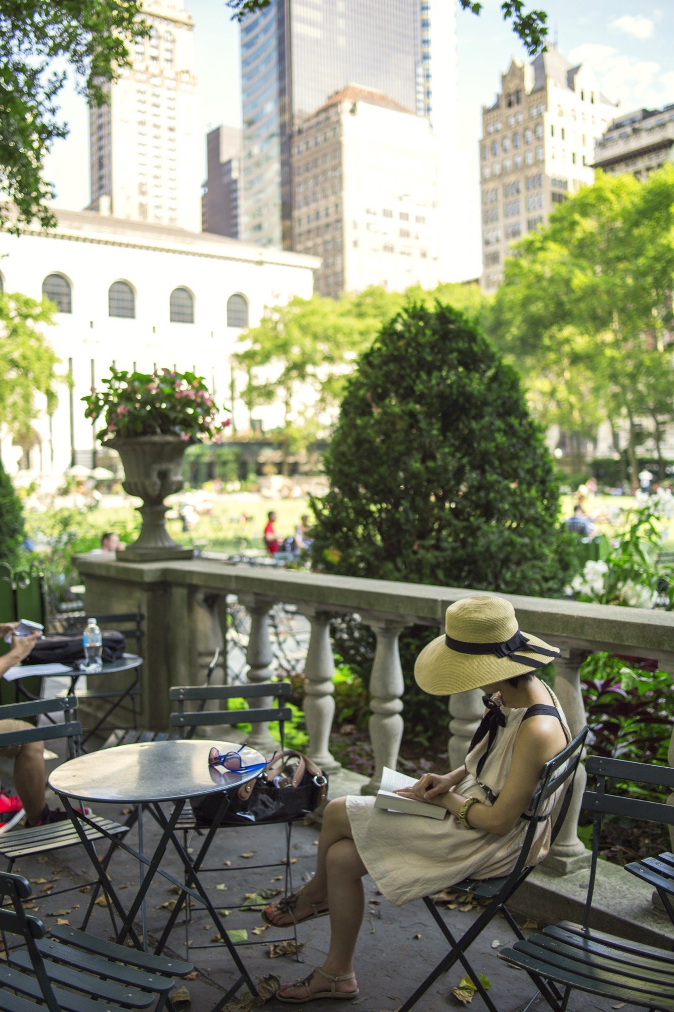 A woman in a sun hat reading in a city park
