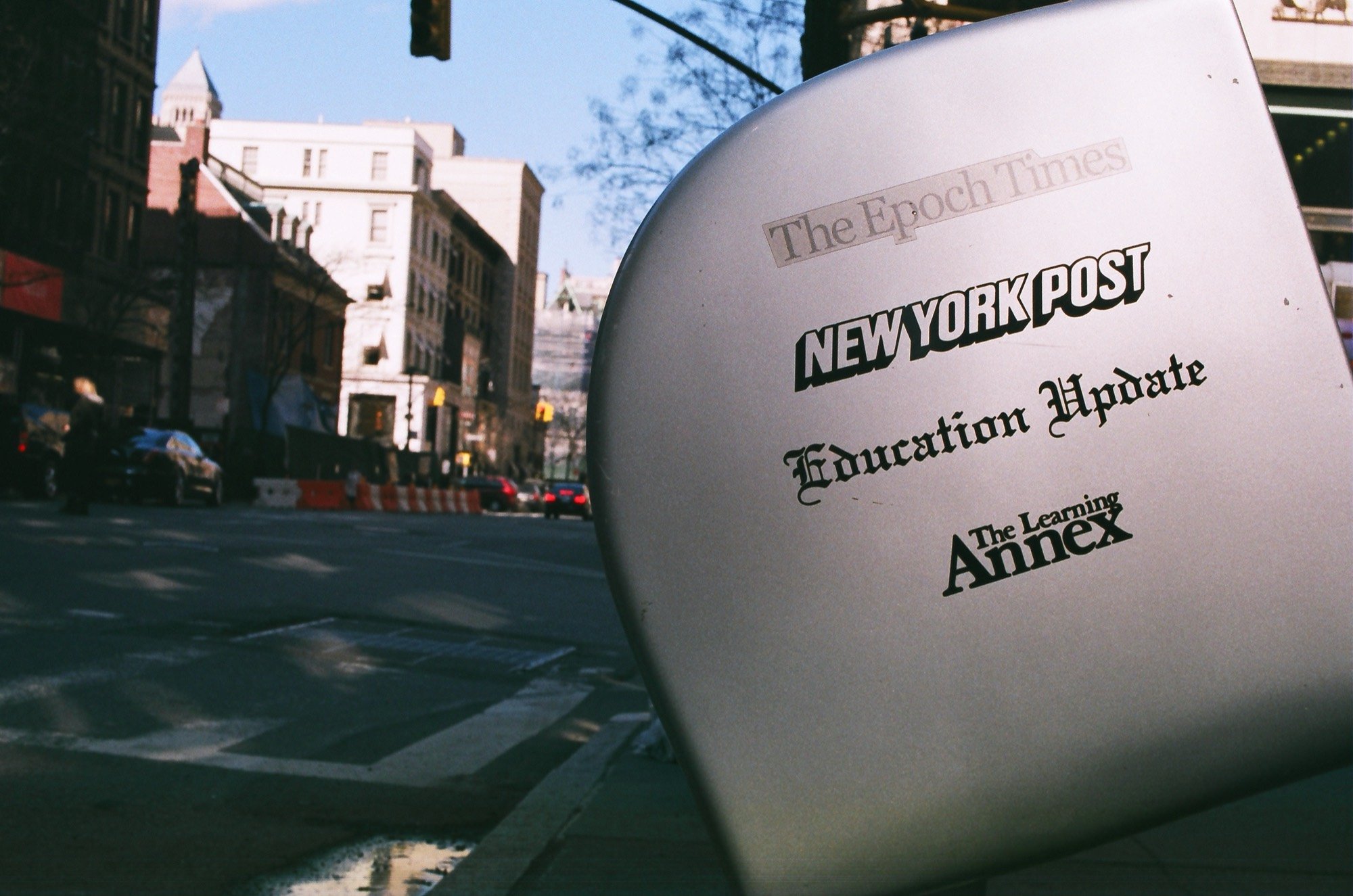 A newspaper box on a sunny city street corner