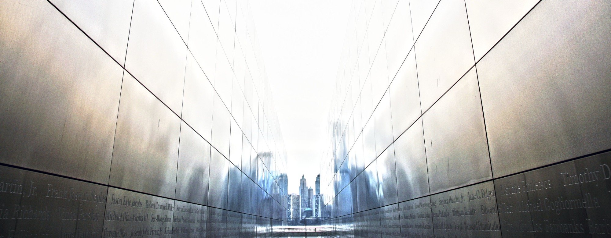 A steel memorial corridor framing the Manhattan skyline