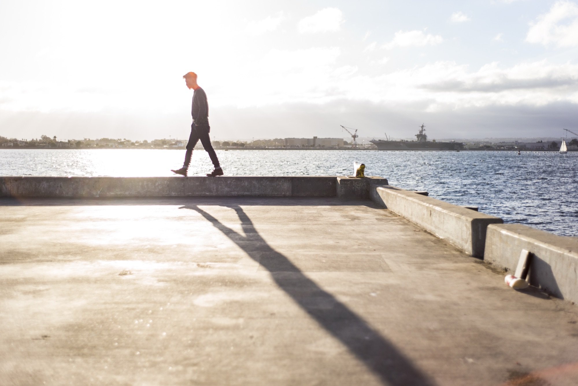 A man walking along a pier ledge