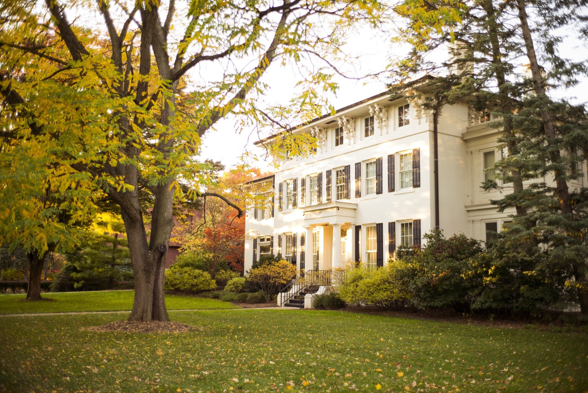 A white colonial house on an autumn lawn