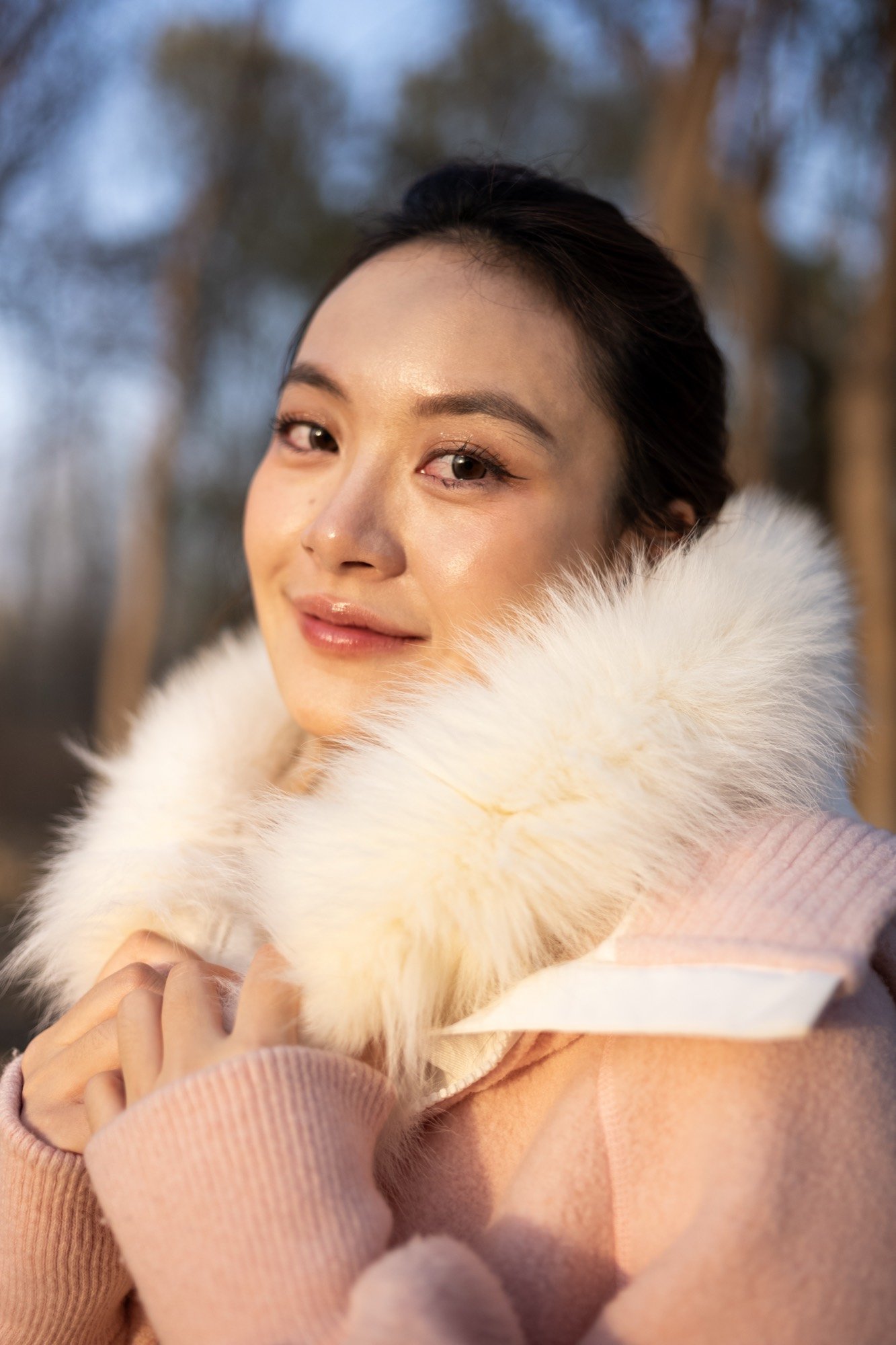 A woman in a fur-collared coat in warm winter light