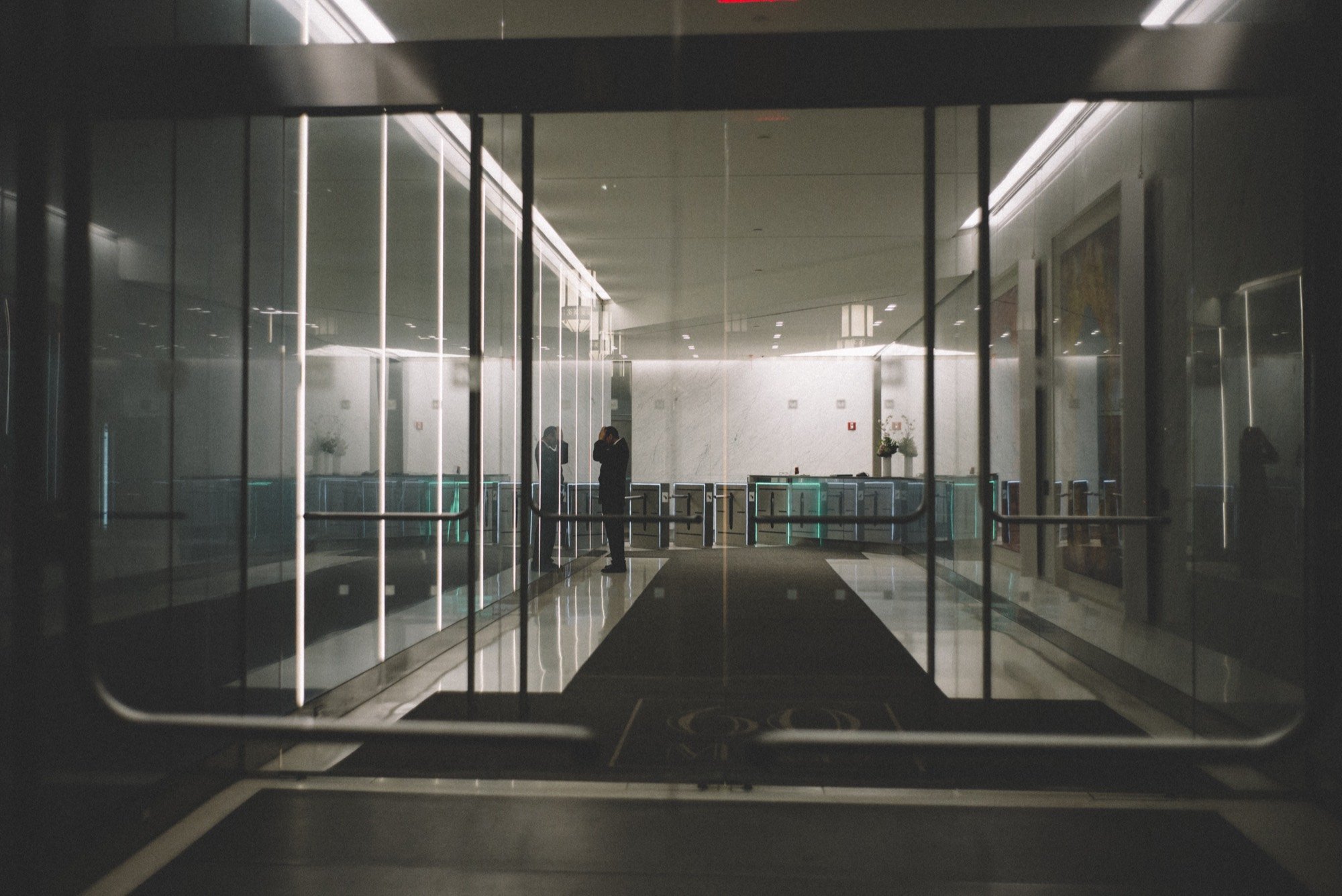 A figure silhouetted in a glass office lobby