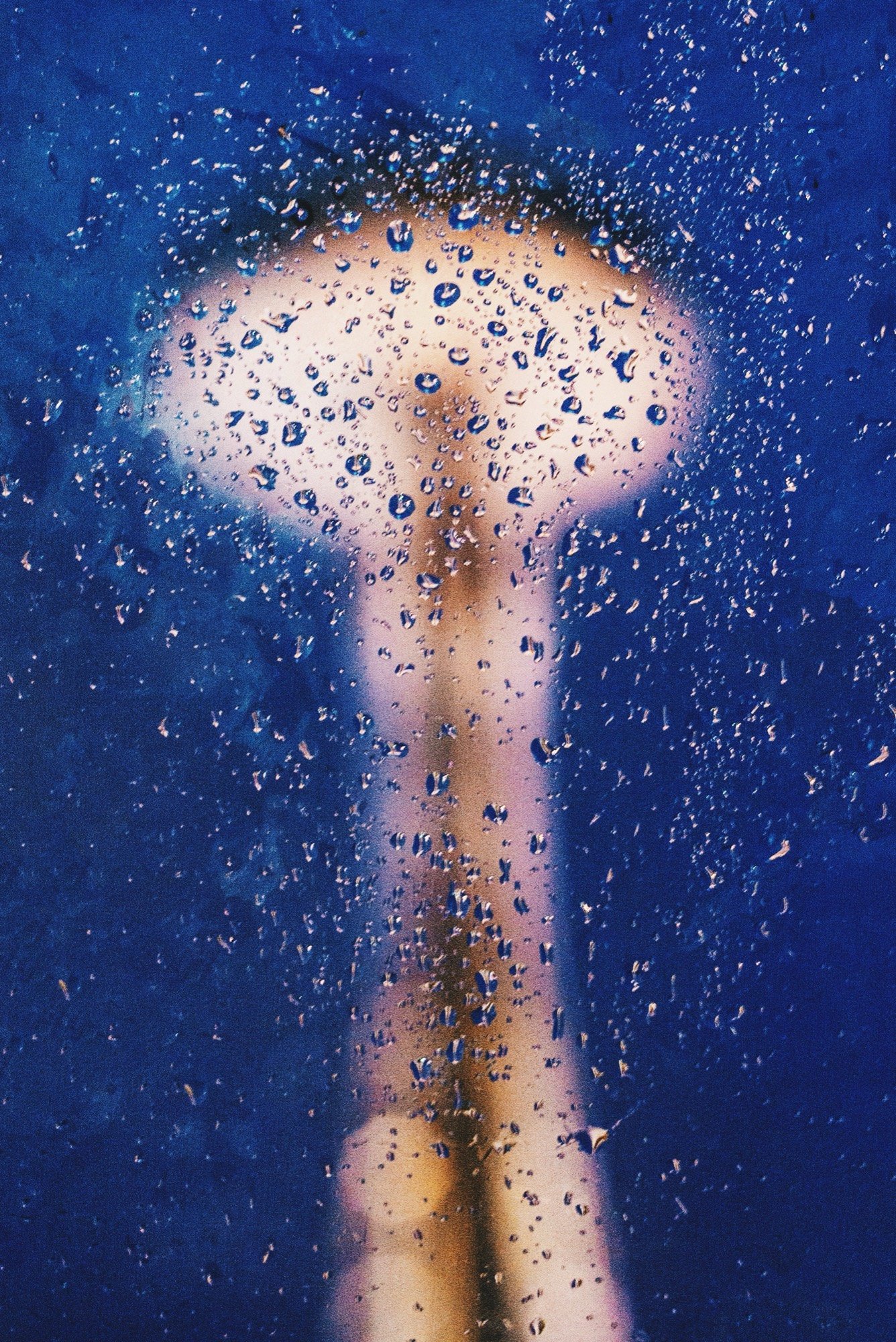 A glowing fountain abstracted behind water-flecked glass