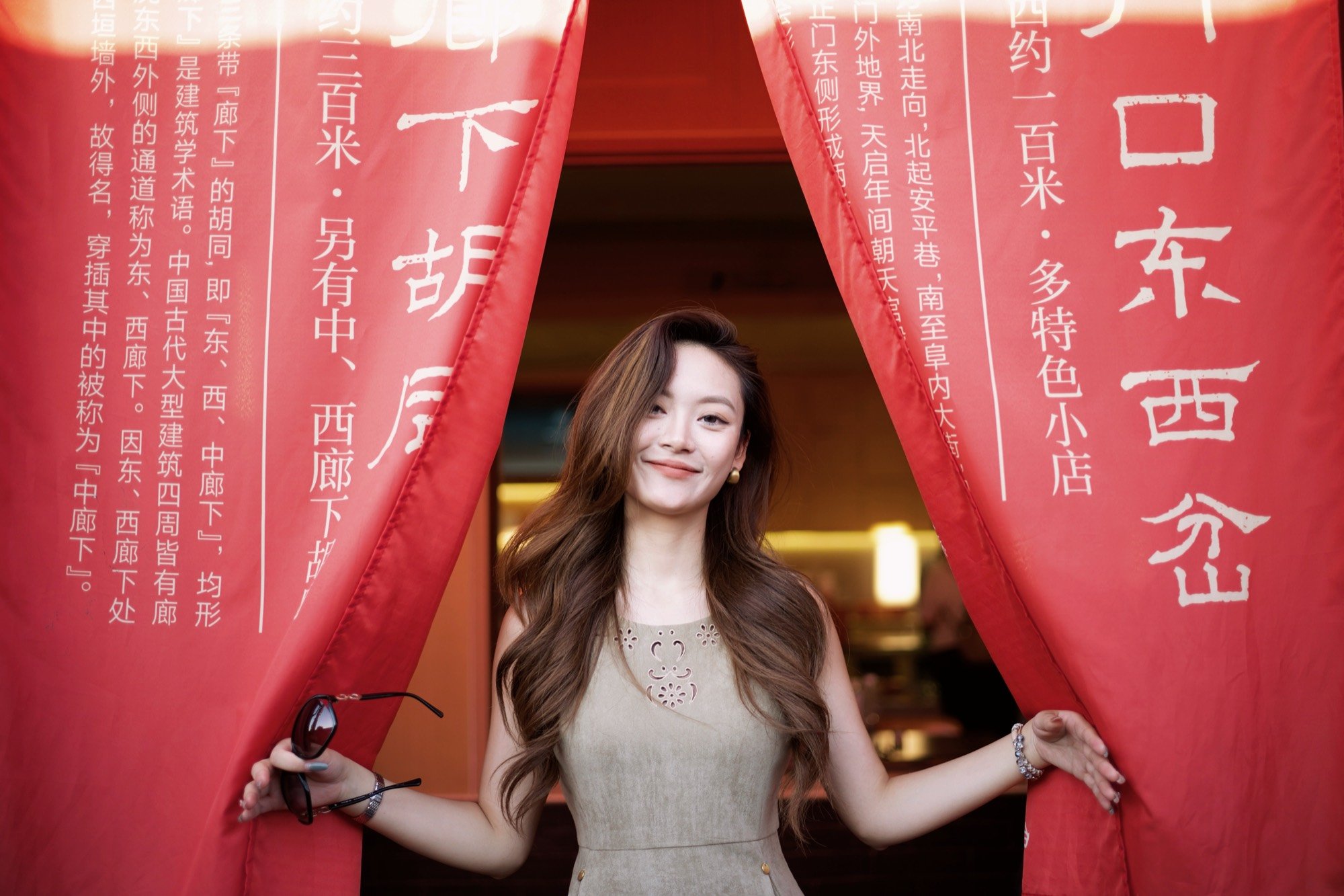 A woman smiling between red banners in a hutong